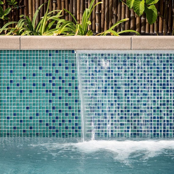 Closeup of pool shelf fountain covered with blue and green mosaic tile.