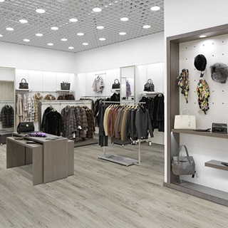 Retail clothing store with luxury vinyl flooring that looks like light gray wood floor, racks with clothing, and hats hanging from a peg board.