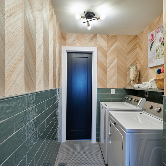 Laundry room with wood wall façade, green subway tile wainscot, natural quartzite shelf, washer & dryer, gray penny round mosaic floor tile.