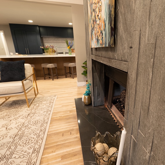 Family room fireplace with black soapstone on the hearth and dark gray random linear mosaic porcelain tile on the façade.