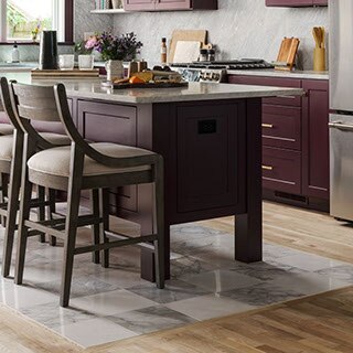 Renovated kitchen with plum-colored cabinets, gray marble backsplash and countertops, island on top of checkerboard ‘tile rug’ of white marble tile and gray marble tile.
