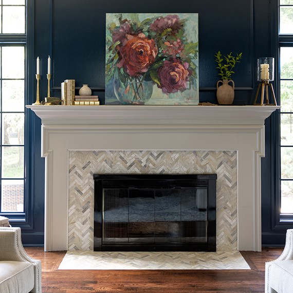 Renovated living room with dark blue paneled walls, fireplace with gray & beige marble mosaic surround and hearth, and white mantel.