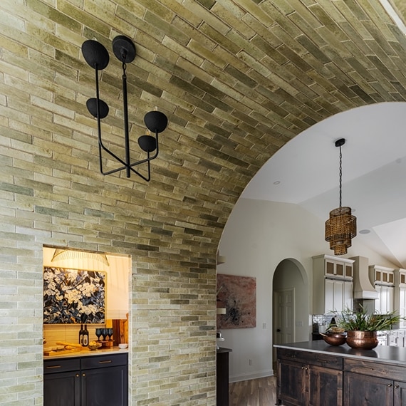 Renovated home with arched entryway covered by glossy brown tile.