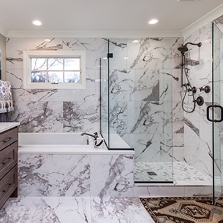 Renovated bathroom featuring white & gray veined porcelain slab that looks marble slab on the wall, tub surround, and shower walls.