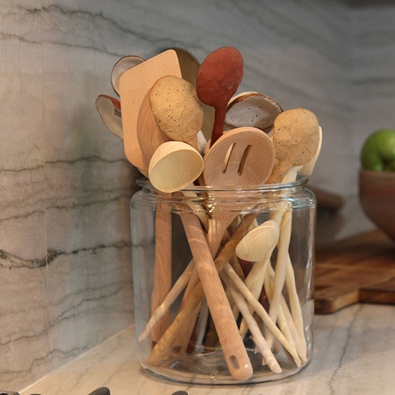 Closeup of glass jar with wooden spoons on a taupe natural quartzite countertop.