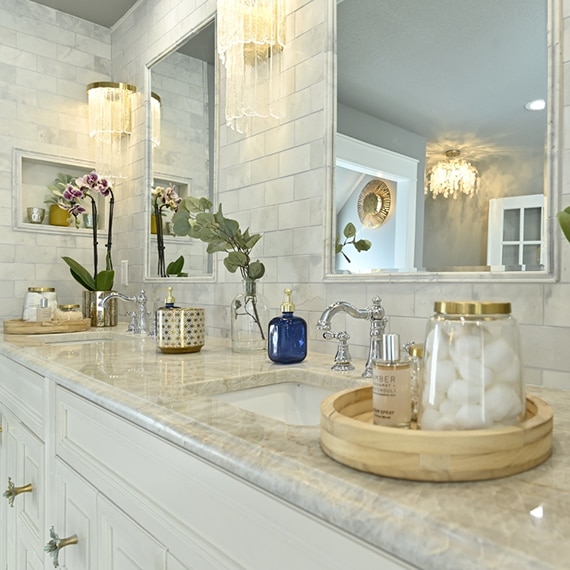 Bathroom vanity with dual undermount sinks, natural quartzite countertops, marble subway tile, marble framed mirrors, and wall niche.