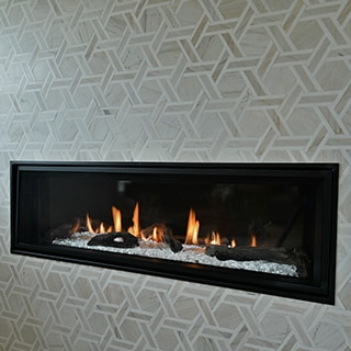 Closeup of wall-mounted fireplace with tan marble and limestone rotating hexagon mosaic wall tile.