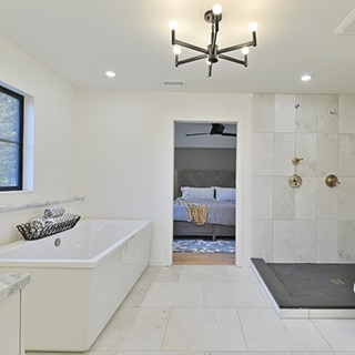 Open concept bathroom with white marble 24x24 tile floor, freestanding bathtub, dark gray mosaic shower floor tile, brushed nickel shower fixtures.