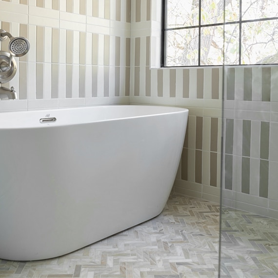 Wet room (freestanding bathtub in walk-in shower) with cream & tan striped wall tile and tan & white herringbone marble shower floor tile.