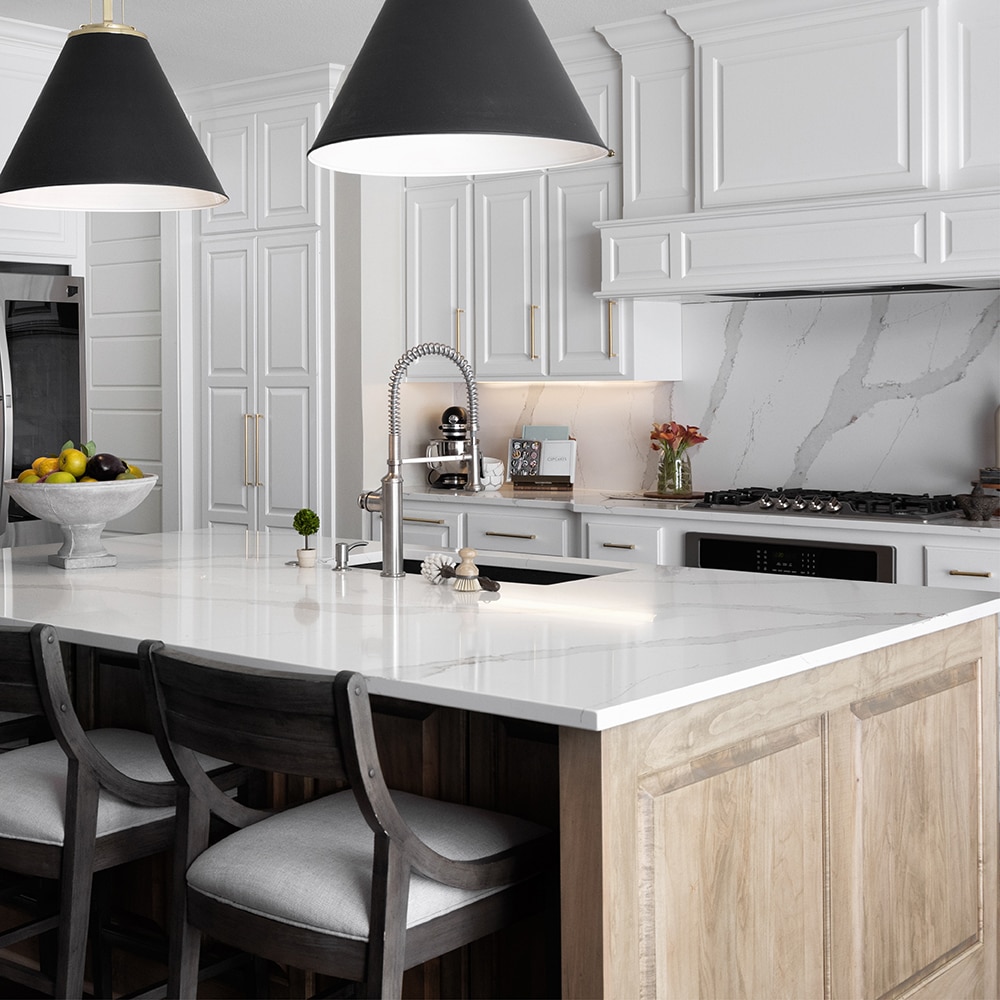 Kitchen with center island, white cabinets, white sitting chairs, and white marble countertops and backsplash.