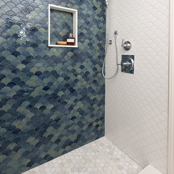 Bathroom shower showing a blue fan mosaic tile on the side wall, a white fan mosaic on the back wall, and a white marble look hexagon mosaic on the shower floor.