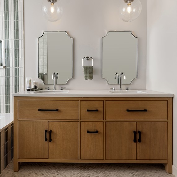 Bathroom showing his and hers sinks with a white monochromatic countertop and a shower on the edge showing undulated green and white shower tile.