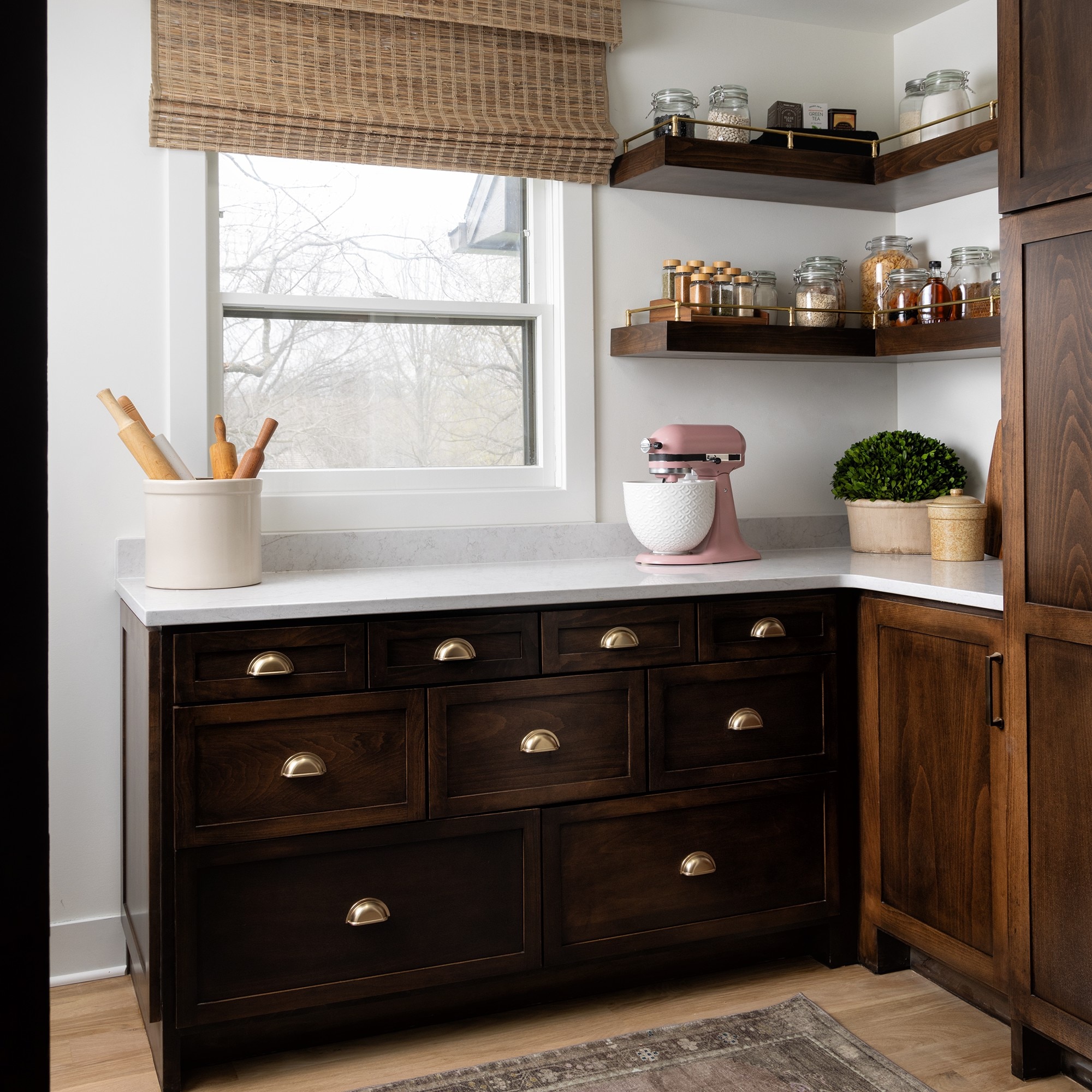 Kitchen pantry with white quartz countertop and dark brown wood cabinets.