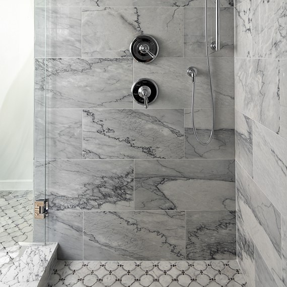 Shower with white marble look tile on the walls and a white marble look ring mosaic on the shower floor.