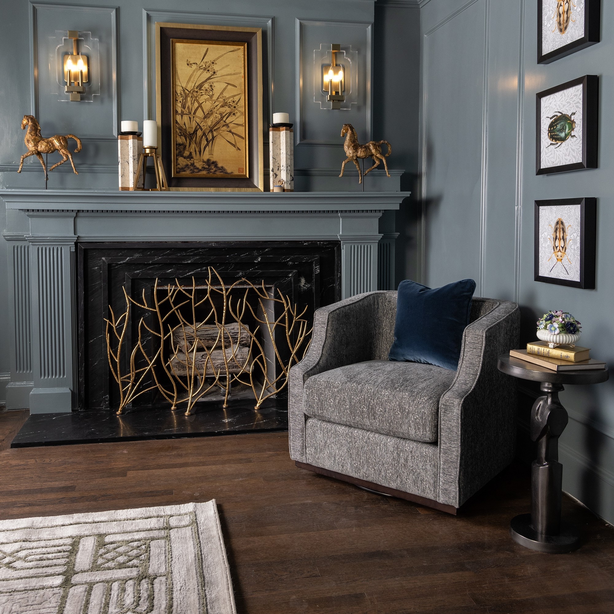 Light blue fireplace with black marble look slab surrounding fireplace, gold decorations, and a gray couch.