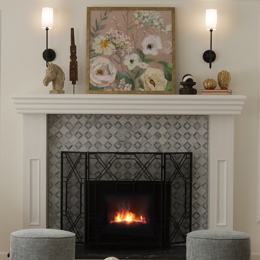 Fireplace against a white wall, gray sitting stools, and gray marble look mosaic surrounding the fireplace.