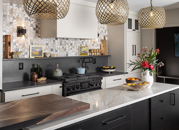Kitchen with center island, black countertop and backsplash, white marble countertop on center island countertop, white marble mosaic, and black and white cabinets.