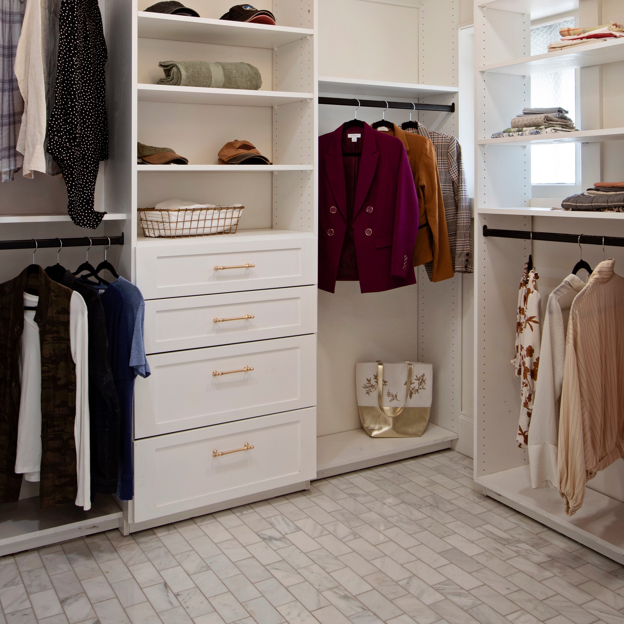 Closet with clothes on white shelves and drawers, and white marble look brick joint floor tile.