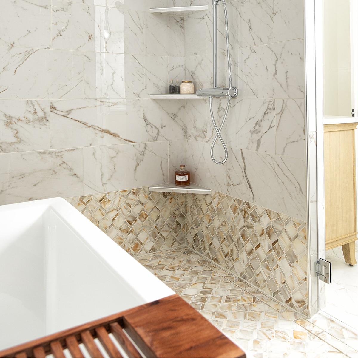 Shower with ith white marble look mosaic on the shower floor and bottom half of the wall, and white marble look rectangle tile on the top half of the wall.