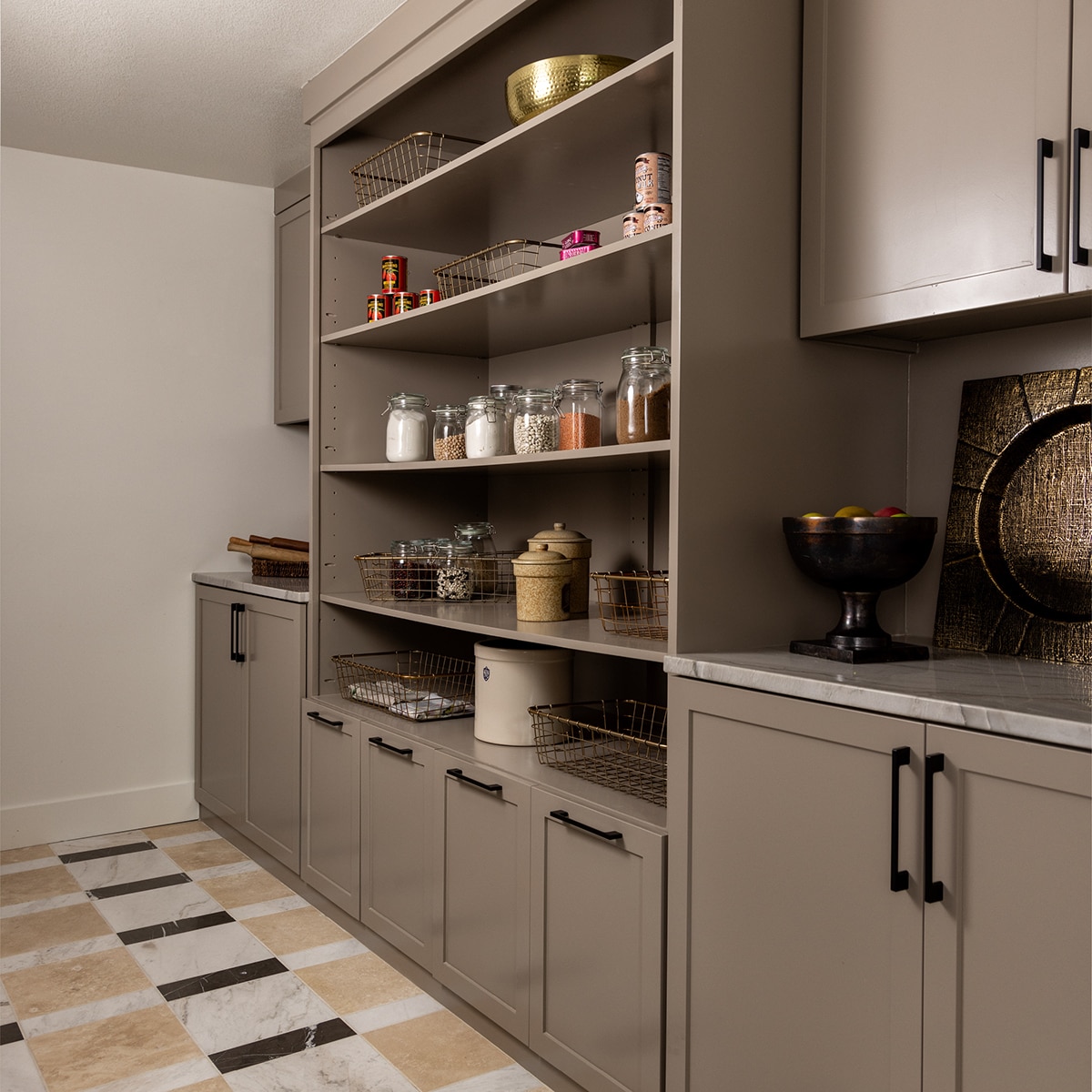 Pantry with gray cabinets, a white quartzite countertop, a checkered floor with white marble look floor tile, gray marble look floor tile, and beige natural stone floor tile.