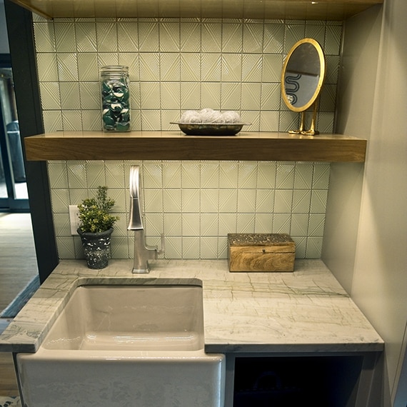 Mudroom sink with a green mosaic backsplash, a gray quartzite countertop on the sink, and gray cabinets.