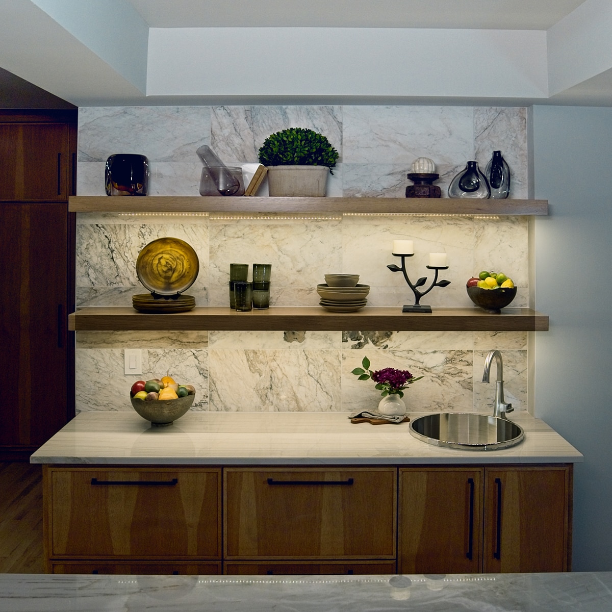 Breakfast bar with a white marble look tile on the wall, a white quartzite countertop, and wood cabinets.