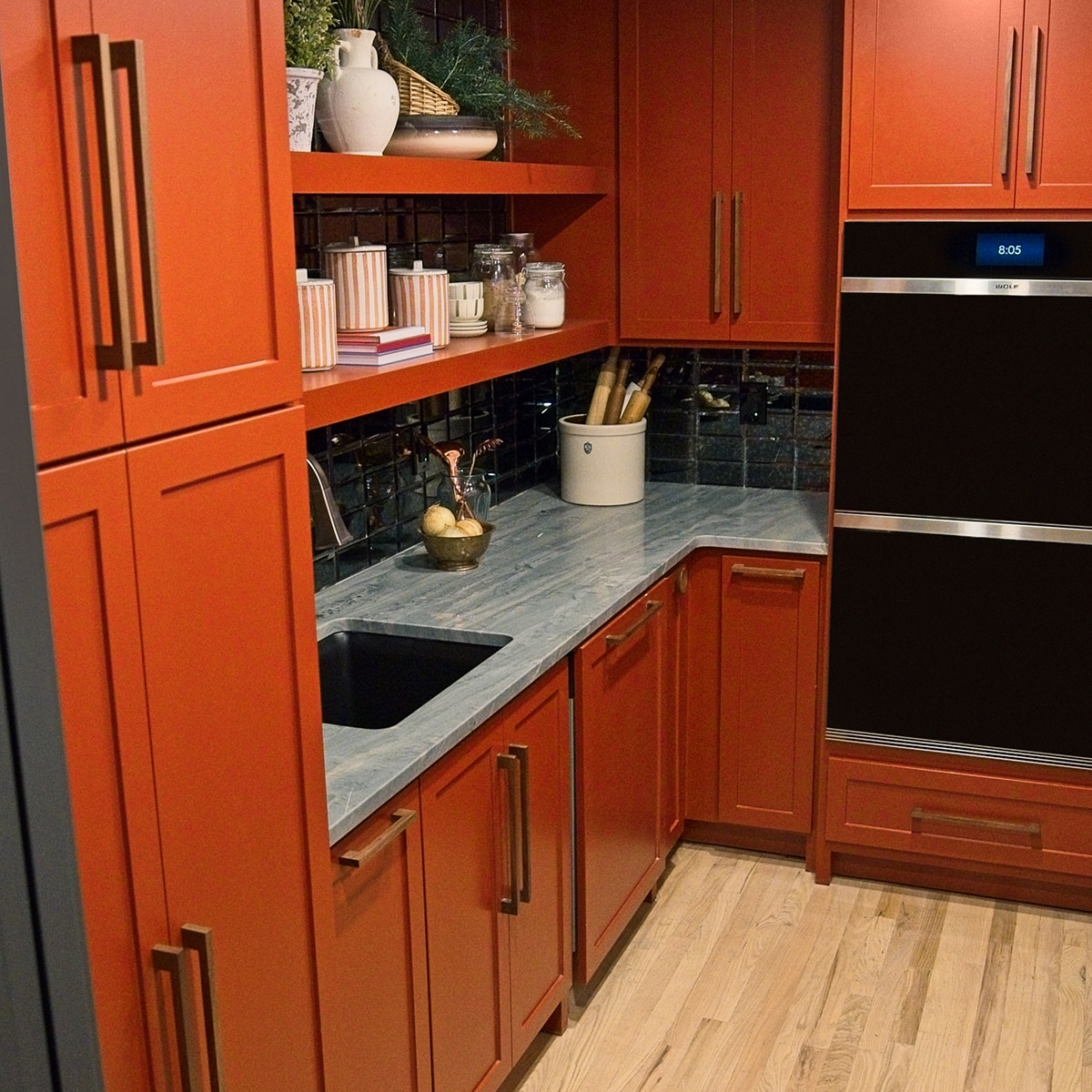 Pantry with orange cabinets, a black mosaic on the backsplash, and a gray quartzite countertop.