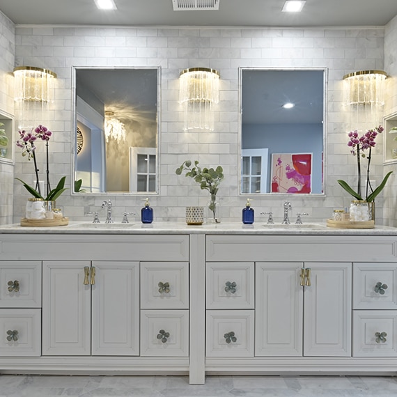 Bathroom vanity with white cabinets, dual sinks, natural quartzite countertops, marble subway tile, marble framed mirrors, and two wall niches.