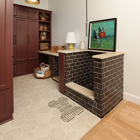 Kitchen pantry with a beige stone look hexagon floor tile and a dog washing station with brown subway tile on the walls and a black hexagon mosaic tile on the floor.