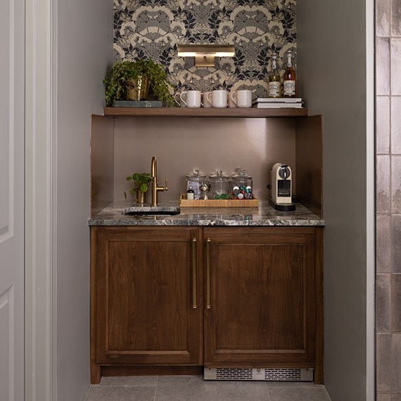 A coffee bar with brown cabinets accented by a brown stone marble slab on the countertop, adorned with various coffee supplies.