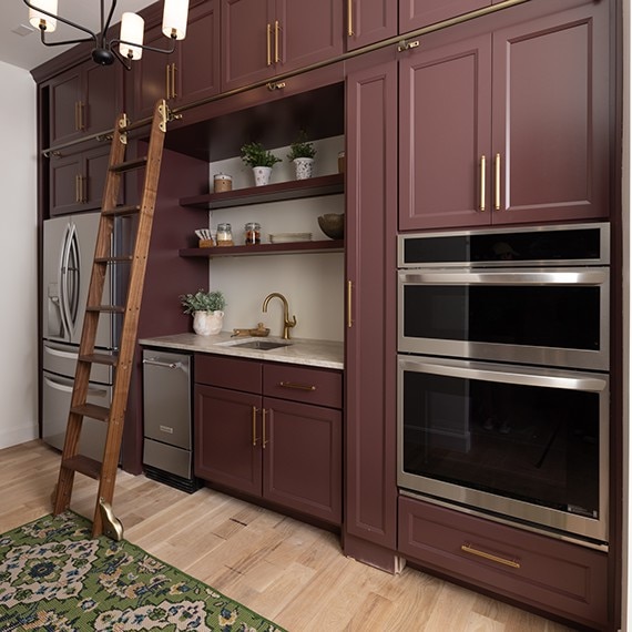 Kitchen with red cabinets and silver appliances accented by a beige quartzite slab on the countertop.