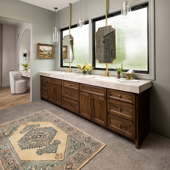 Bathroom his and hers sinks with brown cabinets, beige marble look quartzite slab on the countertop and light gray stone look square floor tile.