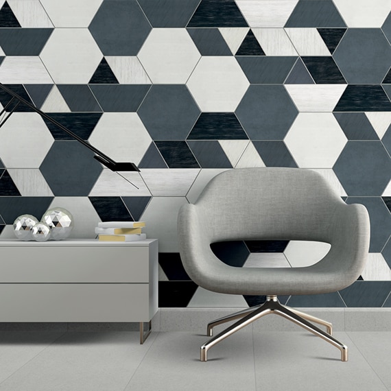 Eye-catching feature wall with white, gray and black hexagon tile, gray chair, gray credenza holding desk lamp and books, and gray floor tile.