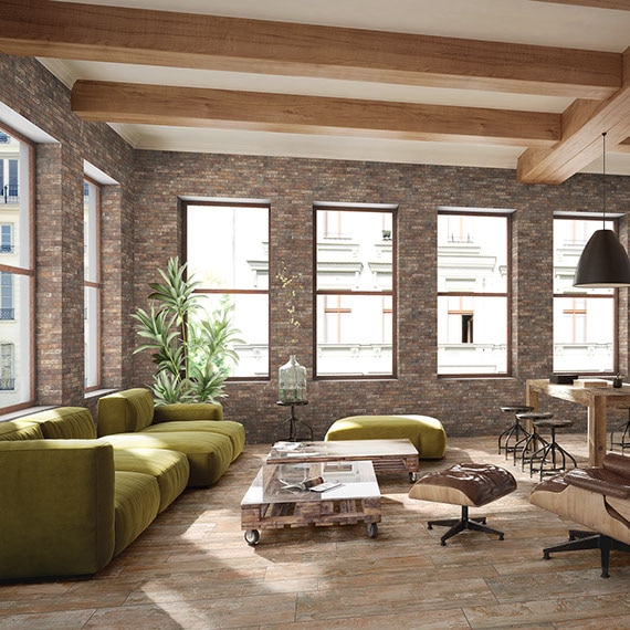 Large living room with wood-look floors and red brick-look porcelain tile walls. Light green sofas and light wood furniture.