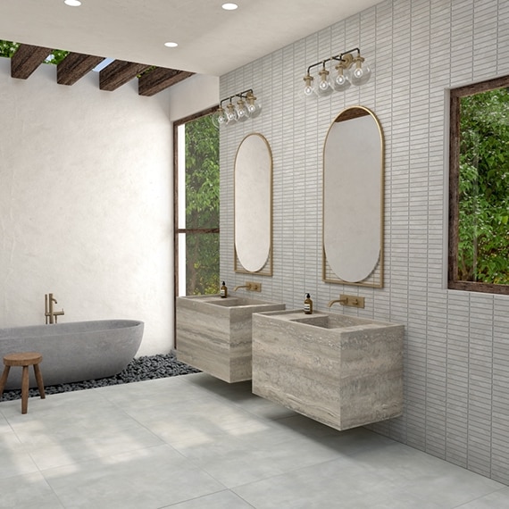 Bathroom with gray soaker tub set in pebbles, gray stone look tile flooring, dual floating vanities that look like gray natural quartzite, and gray 1x6 mosaic backsplash.