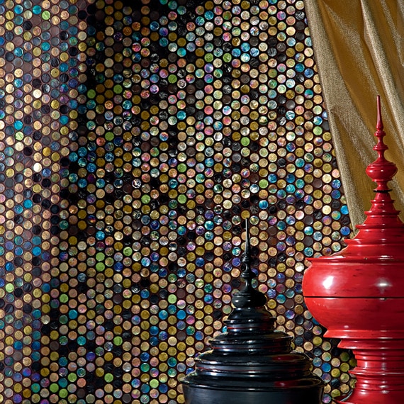 Closeup of wall with round gold, blue, and black iridescent mosaic tile, gold curtain, black and red vases.