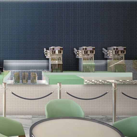 Ice cream parlor with beige mosaic wall tile, navy mosaic feature wall, mint countertop, gray marble floor tile, and white & gray tables with mint chairs.