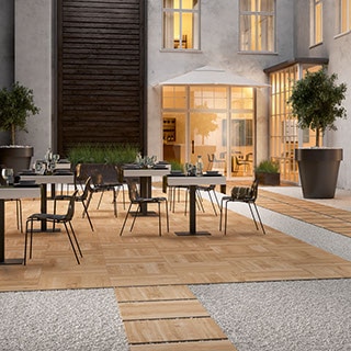Outdoor hotel restaurant with 24” x 24” 2 centimeter porcelain pavers that look like elm wood for dining area flooring and walkway set in gravel.