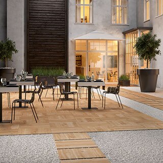Outdoor hotel restaurant with 24” x 24” 2 centimeter porcelain pavers that look like elm wood for dining area flooring and walkway set in gravel.