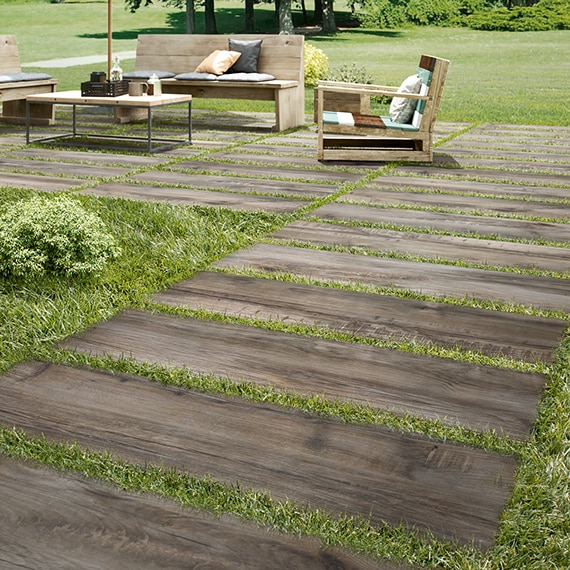 Lawn furniture on 16" x 48" 2 centimeter porcelain pavers that look like seasoned wood, set on top of green grass.