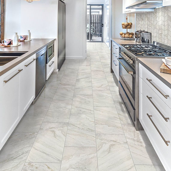 Kitchen with white with tan & gray veining marble look floor tile and matching chevron mosaic backsplash, white cabinets and tan countertops.