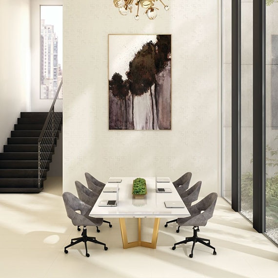 Conference room with off-white textured wall, white stone-top table with brown suede chairs, off-white floor tile.
