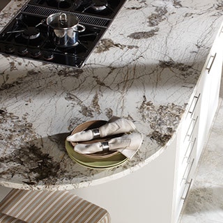 Rounded edge kitchen peninsula with cooktop and dramtic dark gray and white natural stone countertop.