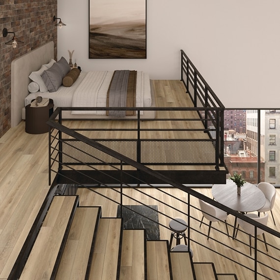 Loft apartment with LVT that looks like wood planks on floor and stairs, dining table and chairs, upstairs bedroom, windows with city view.