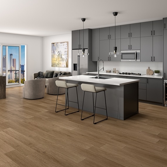 Highrise apartment with LVT that looks like wood planks, white quartz kitchen countertops with sink in island, gray cabinets, windows with city skyline view.
