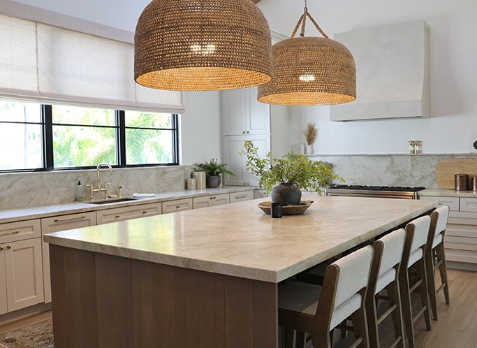 Kitchen with center island, white cabinets, white quartzite countertops and backsplash, and light wood floor.
