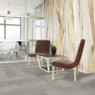 Office foyer with luxury vinyl tile that looks like gray concrete flooring, brown leather chairs and side table in front of natural wood panel wall.