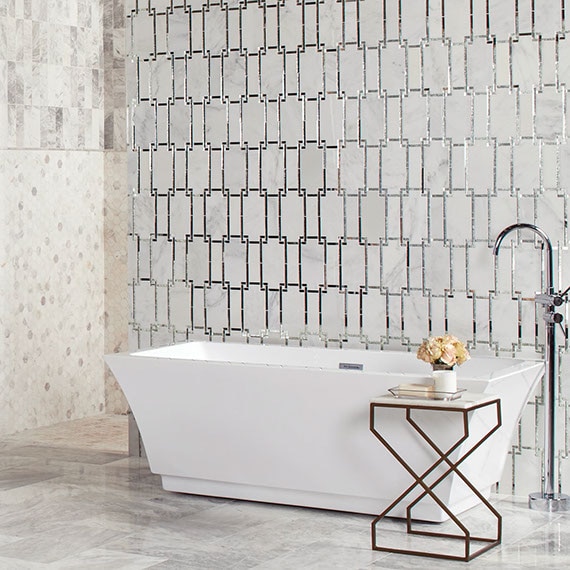 Elegant bathroom with gray marble floor tile, marble & mirror wall tile in front of free-standing bathtub, and marble mosaic shower wall.