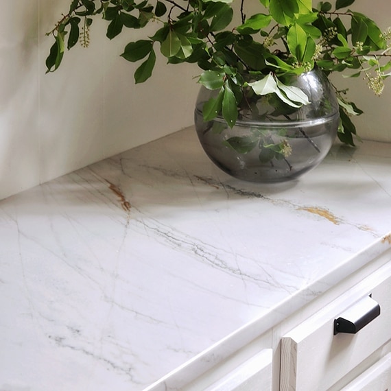 Closeup of natural quartzite countertop on butler's pantry with glass vase holding greenery.