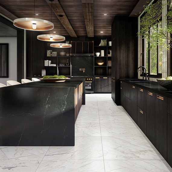 Kitchen with black cabinets, black countertops, center island, and white marble look floor.